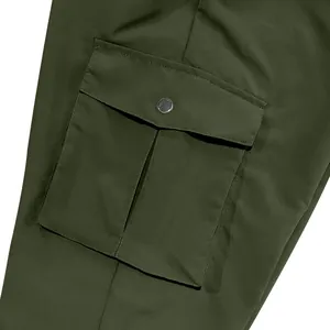 Close-up detail of a cargo pocket on olive green work pants with metal snap closure
