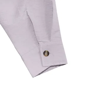 Macro detail showing the linen shirt cuff with button and natural fabric texture