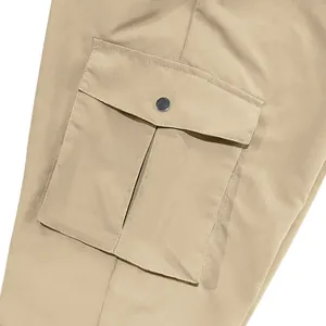 Close-up of a large functional cargo pocket with metal button on khaki utility trousers.
