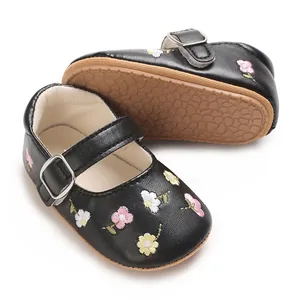 Nahaufnahme von schwarzen Babyschuhen für Mädchen mit Blumenstickerei und Gummisohle