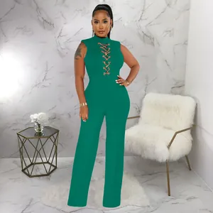 Model wearing a dark green sleeveless high-neck jumpsuit with chain lace-up chest detail