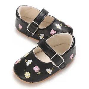 Detailaufnahme von schwarzen Baby-Mary-Janes mit Blumenstickerei und rutschfester Gummisohle