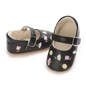 Detailaufnahme von schwarzen Baby Mary Janes mit zarter rosa und weißer Blumenstickerei