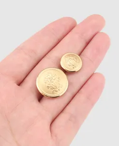 Macro view of high-end Japanese brass buttons featuring an embossed crest design on a palm