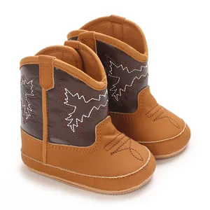 Vue détaillée de bottes de cowboy marron pour bébé avec surpiqûres décoratives blanches