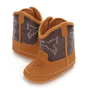 Vue détaillée de bottes de cowboy marron pour bébé avec broderies blanches et motifs
