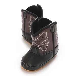 Vue détaillée de bottes western pour bébé en cuir marron avec broderies de feuilles.