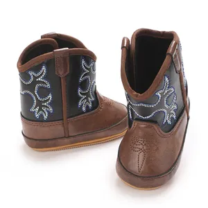 Vue détaillée des bottes de cow-boy marron et noir pour bébé avec de jolies broderies bleues