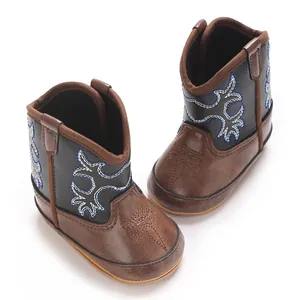Vue plongeante de bottes de cowboy pour bébé avec broderies bleues et blanches détaillées.