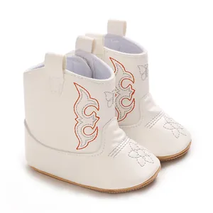 Detailed macro view of white baby cowboy boots with orange floral embroidery detail