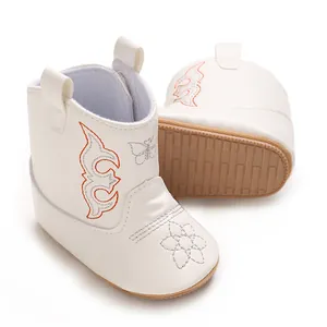 Macro view of white soft PU baby boots with embroidered details and non-slip rubber soles