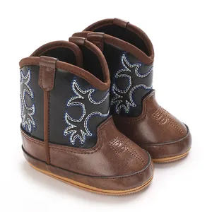 Vue détaillée des bottes de cowboy pour bébé avec broderie bleue et similicuir marron.