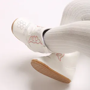 Detailed close-up of white baby boots featuring embroidered patterns and brown non-slip soles