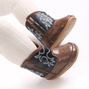 Gros plan détaillé de bottes de cowboy marron pour bébé avec broderie bleue pour automne hiver
