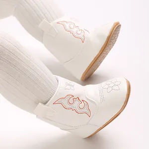 Close-up of white baby boots with orange embroidery and soft anti-slip soles