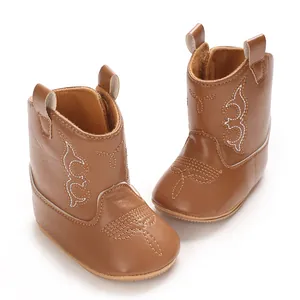 Detail of brown baby cowboy boots with decorative stitching and soft PU leather texture.