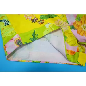 Dettaglio ravvicinato del tessuto della tuta in lino a fiori e cuciture di pregio.