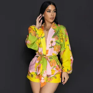 Elegante tuta corta a fiori con maniche lunghe, collo a scialle e cintura sottile.