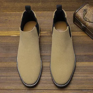 Vue de dessus de bottines Chelsea pour hommes en daim beige sur sol en bois