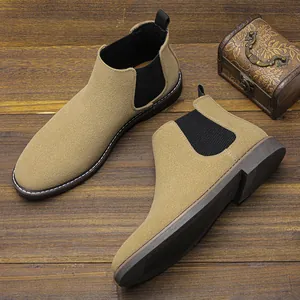 Gros plan détaillé de bottines Chelsea en daim marron clair sur sol en bois sombre