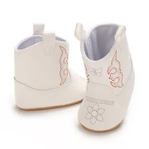 Detailed view of white baby girl walking boots with delicate orange embroidery.