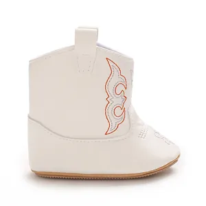 White infant cowboy boots with orange side embroidery and soft leather material.