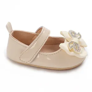 Detailed view of cream baby girl princess shoes with a sparkly rhinestone butterfly bow