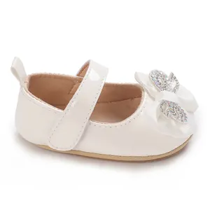 Detailed side view of white baby girl Mary Jane walking shoes with rhinestone bow