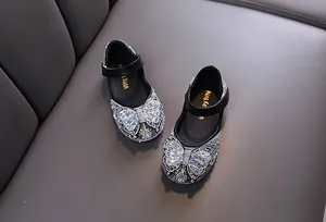 Close-up of sparkling rhinestone butterfly bow on elegant black girls dress shoes
