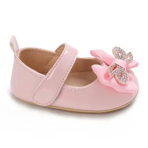 Detail view of pink baby girl princess shoes with a large rhinestone-embellished bow.