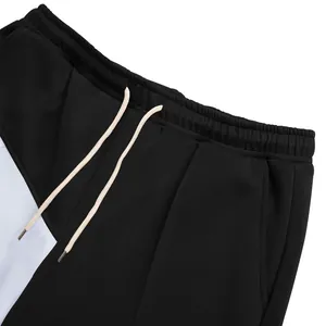 Close-up detail of the elastic waistband and beige drawstrings on men's color-block pants