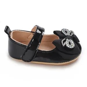 Close-up detail of shiny black patent leather baby girl shoes with rhinestone bow accents