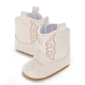 Macro view of stylish white baby girl western cowboy boots with orange embroidery
