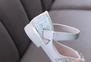 Macro detail of white girls princess shoe featuring sparkling sequins and rhinestone trim