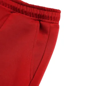 Close-up of red casual joggers featuring elastic waistband and side pocket detail.