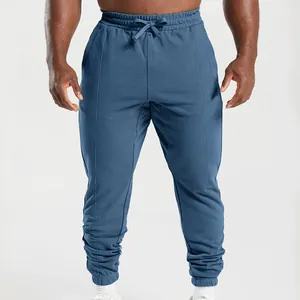 Detail view of men's blue jogger sweatpants with tapered cuffs and drawstring.