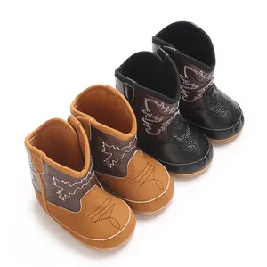 Vue détaillée de deux paires de jolies bottes de cowboy pour bébé en marron et noir.