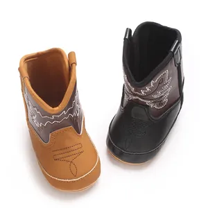 Gros plan de bottes de cow-boy pour bébé fille en marron et noir avec surpiqûres.