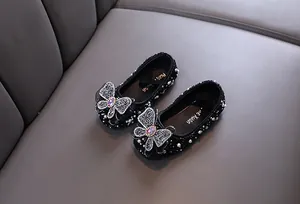 Gros plan de ballerines de princesse noires avec papillon en strass et perles