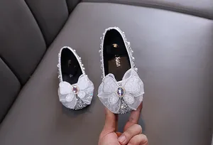Détail des chaussures de princesse argentées avec nœud papillon en dentelle.
