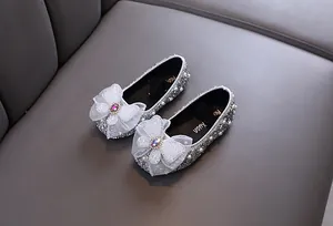 Vue détaillée des chaussures de princesse argentées brillantes pour filles avec perles.