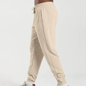 Side view of men's loose beige sweatpants with elastic drawstring waist and cuffed hem