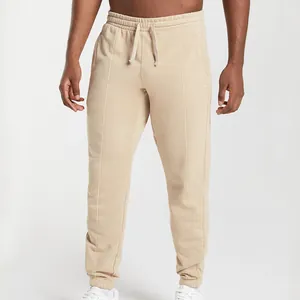 Detail view of men's beige joggers with drawstring waist and central seam detail