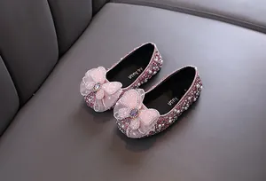 Vue détaillée de chaussures de princesse roses avec strass, perles et un grand nœud.