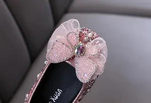 Gros plan sur une chaussure de princesse rose avec nœud strass et perles