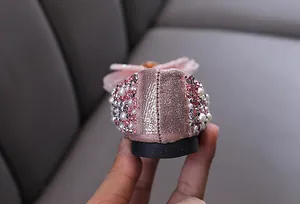 Gros plan sur les détails en strass et perles au talon des chaussures de princesse roses