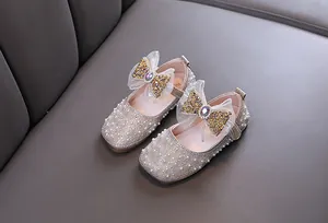 Close-up of girl's princess shoes with pearls, rhinestones, and large glittery bow