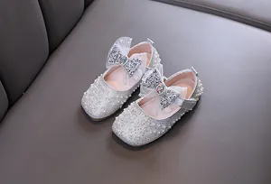 Detailed shot of silver girls Mary Jane shoes with sparkling pearls and rhinestone bow