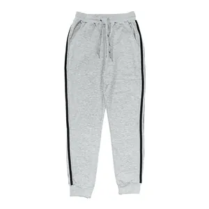 Close-up detail of men's grey joggers featuring black side stripes and ribbed cuffs