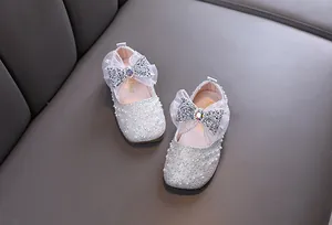 Close-up of white girls princess shoes with pearls, rhinestones, and silver mesh bow